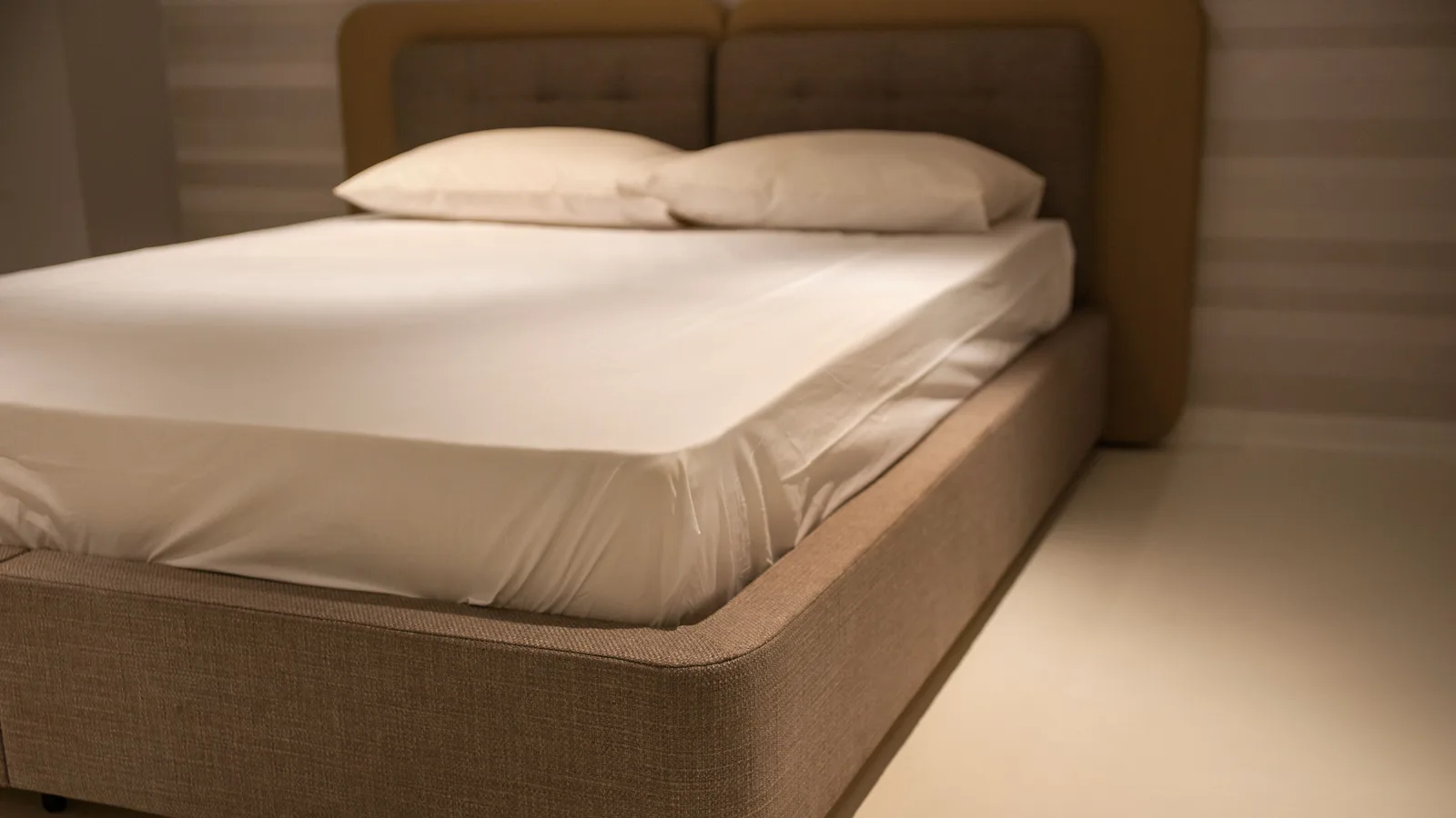 Angle d'un lit double dont le drap-housse s'est déchaussé, laissant apparaître le coin du matelas.