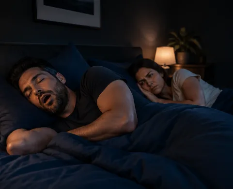 Dormeur allongé sur le côté qui ronfle encore, sa partenaire réveillée à côté de lui.